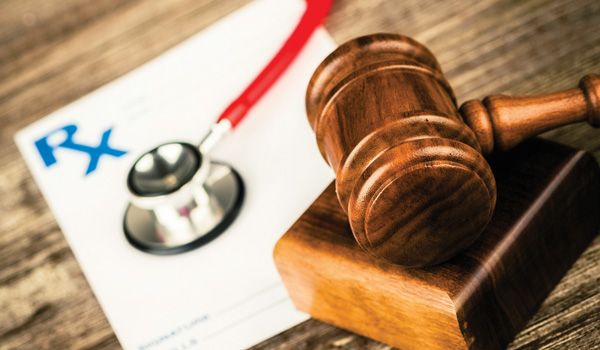 Closeup of a gavel, with a stethescope and prescription in background