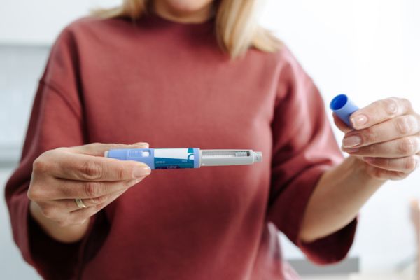 A person holding and preparing a medical injection pen, demonstrating its usage during a healthcare routine.